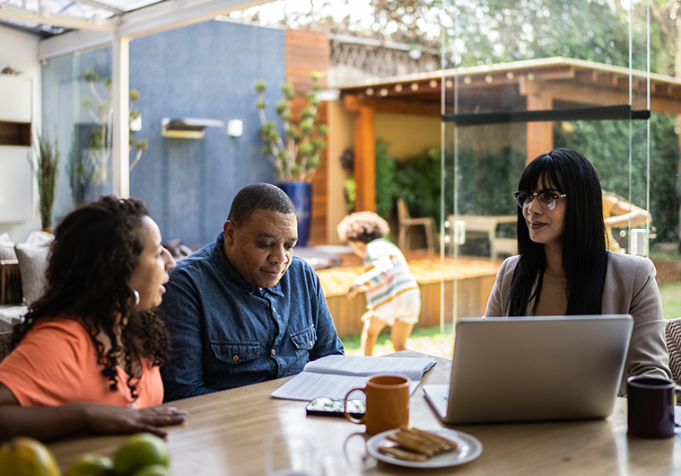 A man and woman sit with a wealth advisor to discuss charitable giving as part of their tax strategy.