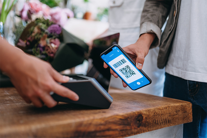 Female customer holds her smartphone to digitally pay for a transaction at a store.