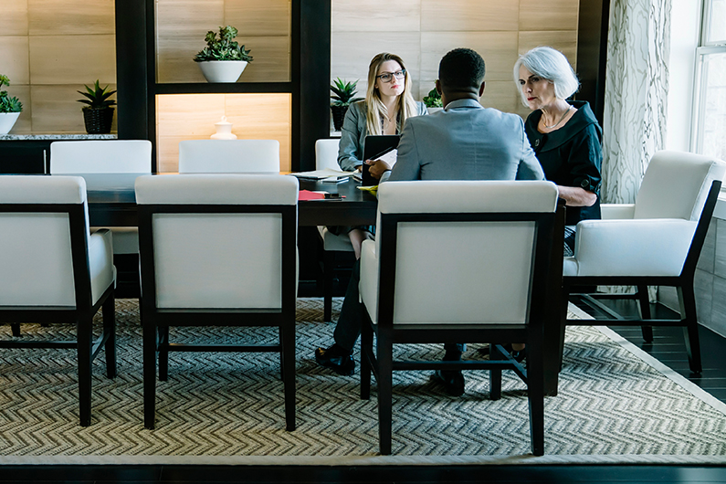 Two people sit at an office desk and review documents.