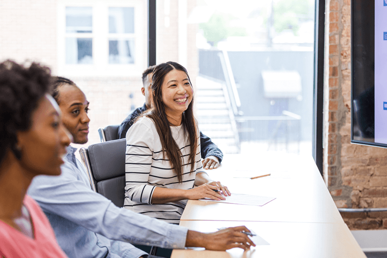 Group of employees gather at a table to address the US workforce shortage and how to recruit employees.