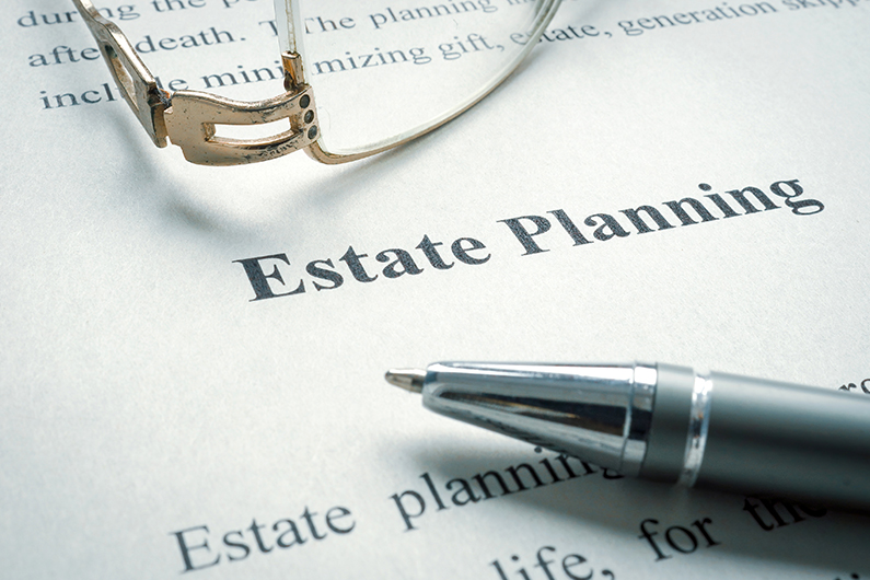 Close-up of a document titled 'Estate Planning' with reading glasses and a pen placed on top.