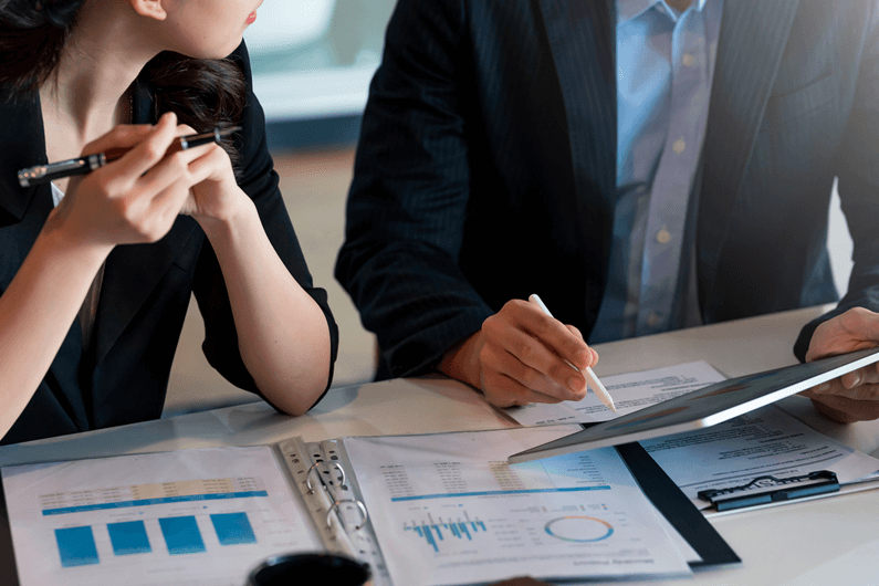 Man and woman in M&A advisory services sit at a white table and review company data.